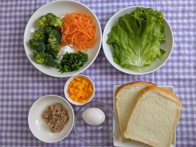 にんじんとねぎ卵とブロッコリーツナのサンドイッチに使う材料を皿に入れてテーブルに置いている写真