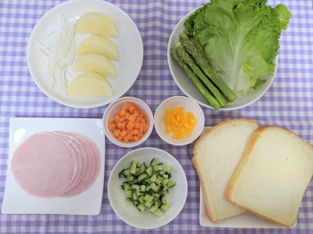 ポテトサラダとハムのサンドイッチに使う材料をお皿に入れてテーブルに置いている写真