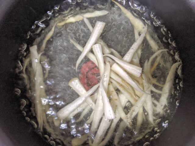 千切りのごぼうを鍋で茹でている写真