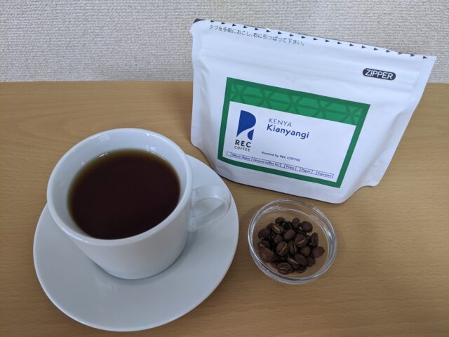 コーヒー専門店REC COFFEEのキアニャンギのコーヒー豆とカップに入れたコーヒーをテーブルに置いた写真