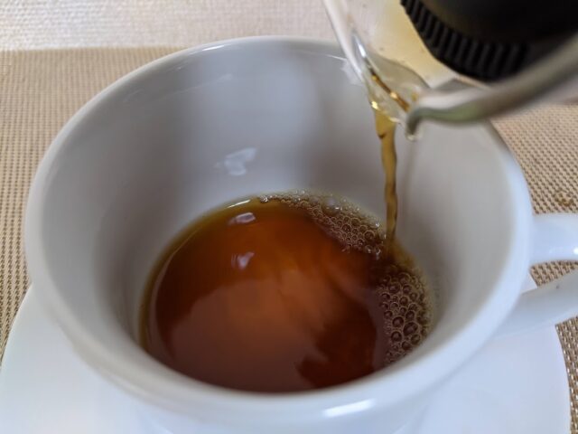 コーヒー豆のキッサブレンドをドリップしたものをコーヒーカップに2/5注いでいる写真
