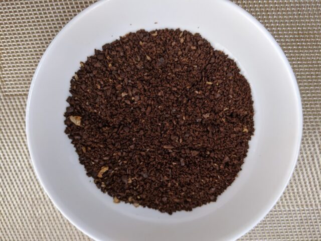 コーヒー専門店「REC COFFEE」のコーヒー豆のキッサブレンドをコーヒーミルで挽いたものをお皿に入れた写真