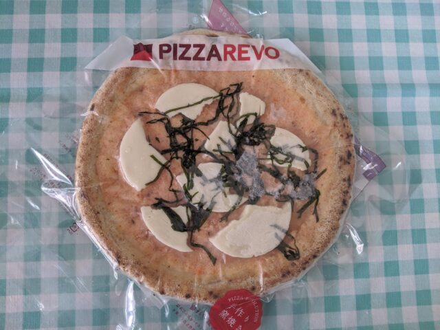 ピザ屋ピザレボの博多明太タラモ大葉冷凍ピザをテーブルに置いている写真