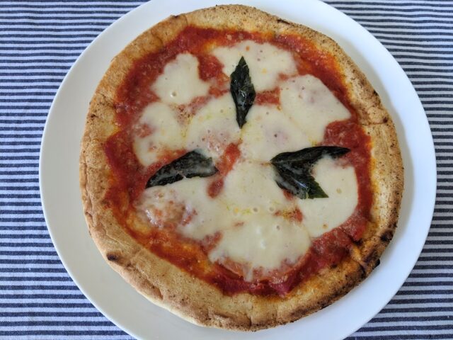 ピザ屋ピザレボの極・マルゲリータの冷凍ピザをオーブンで焼いてお皿に入れテーブルに置いている写真