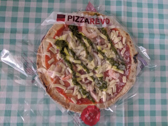 ピザ屋ピザレボの海鮮トマトバジル冷凍ピザをテーブルに置いている写真