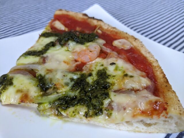 カットしたピザレボの海鮮トマトバジルのピザ1枚をお皿に入れテーブルに置いている写真