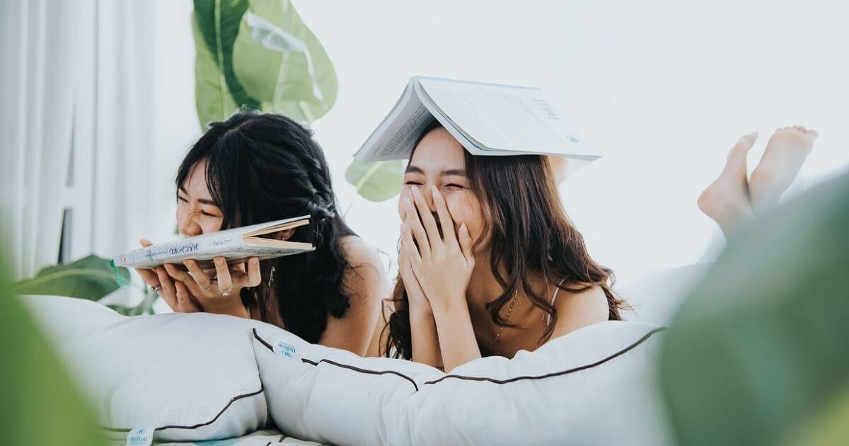 女性が2人寝転がって笑っている画像