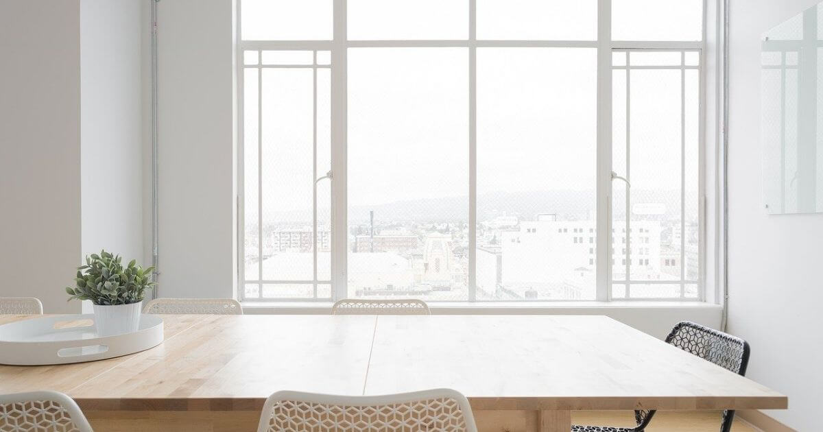 テーブルと窓際の白いカーテンの画像