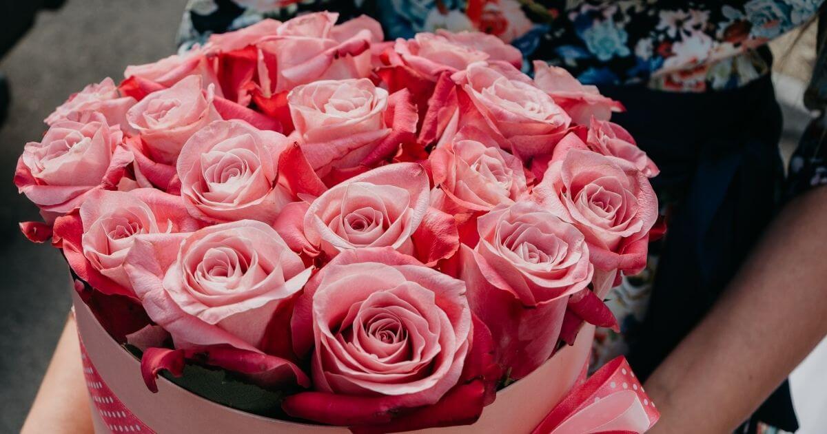 女性がピンクのバラの花束を持っている画像