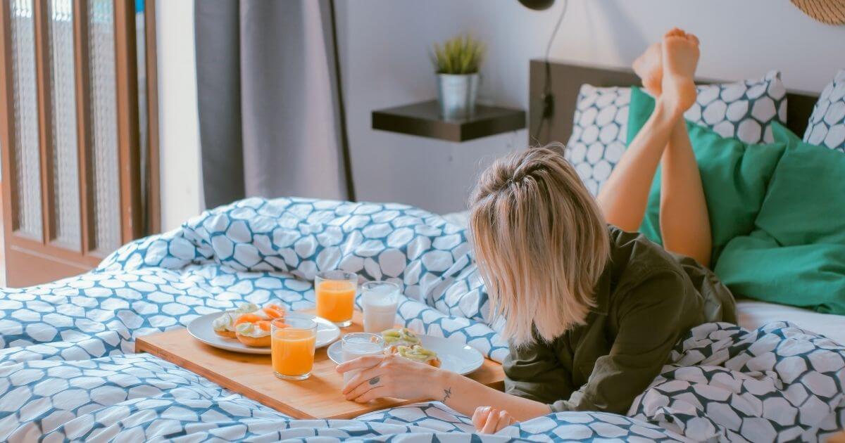 ベッドの上で朝食をしている女性の画像