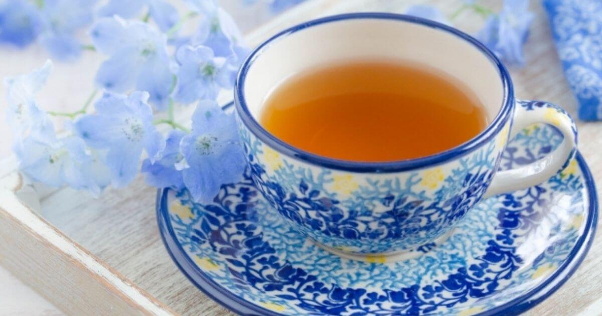青いカップに入った紅茶と青いお花の画像