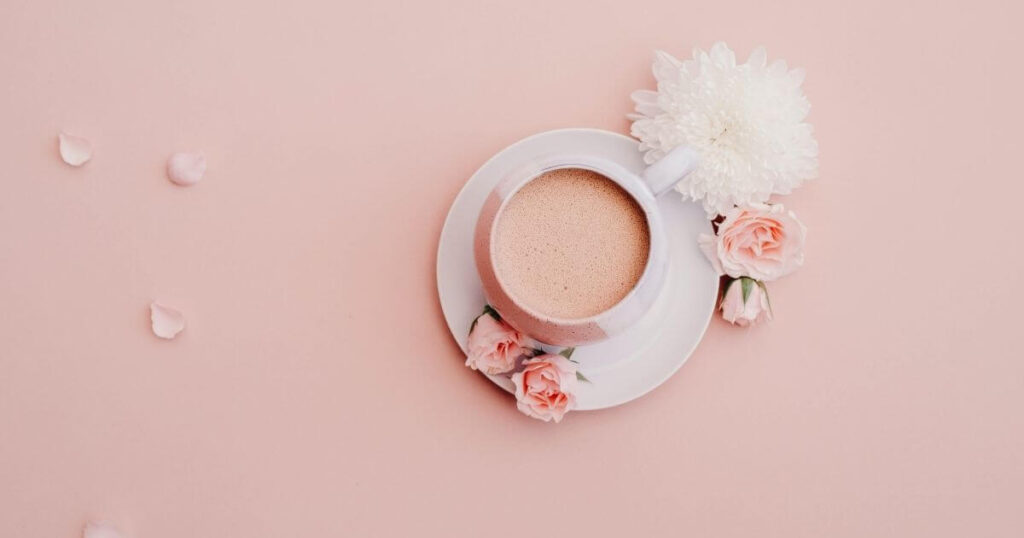 ピンクのテーブルにコーヒーが入っているコーヒーカップとお花の画像