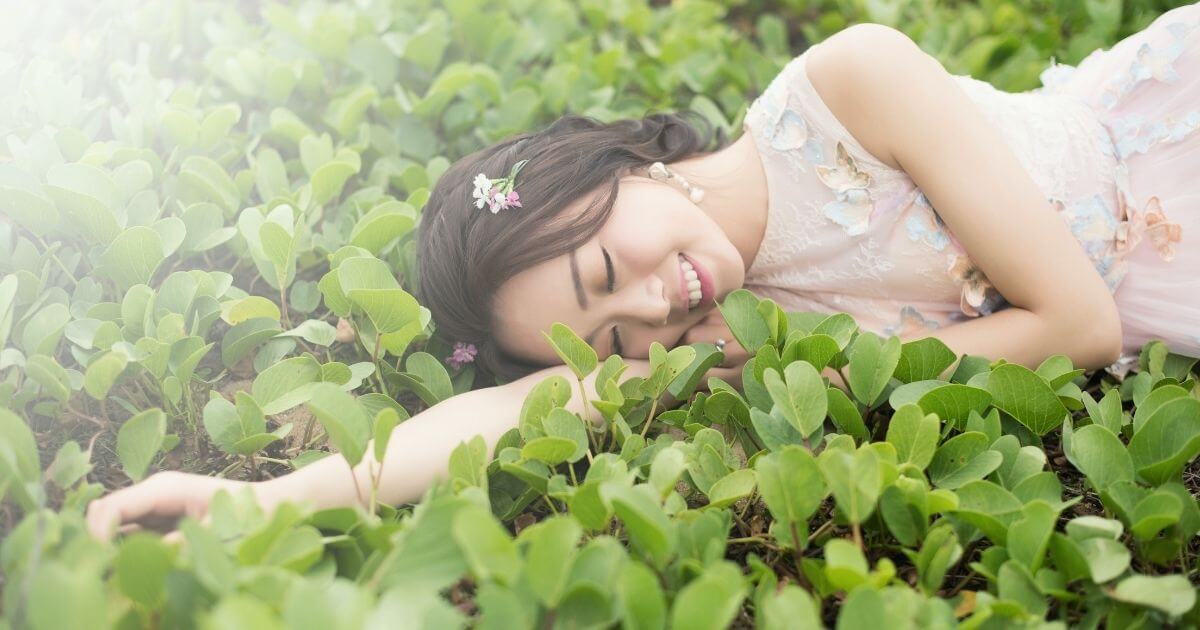 女性が草原に寝転んでいる画像