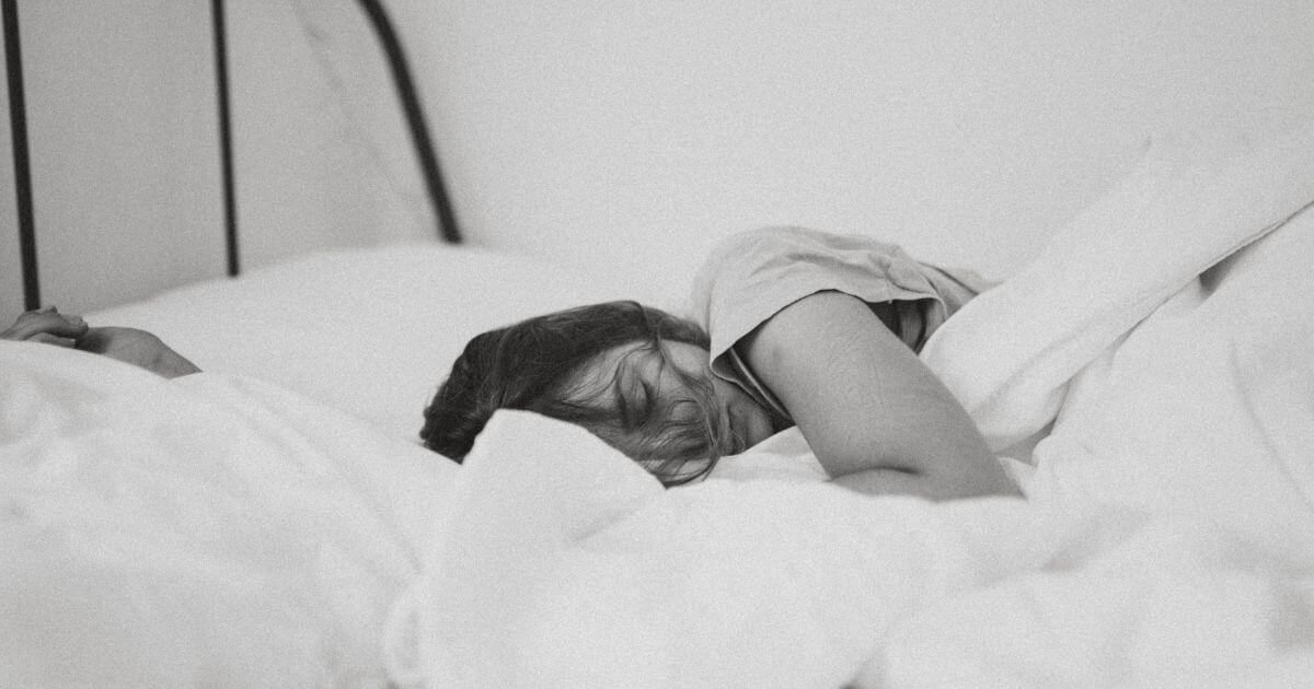 女性がベッドで寝ている白黒の画像