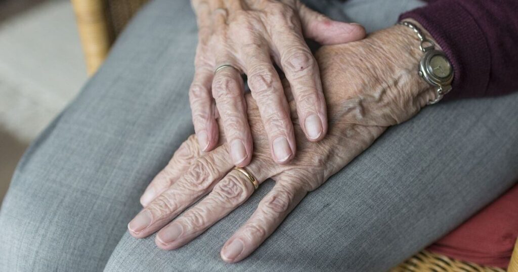高齢者の女性が膝に両手を重ねている画像