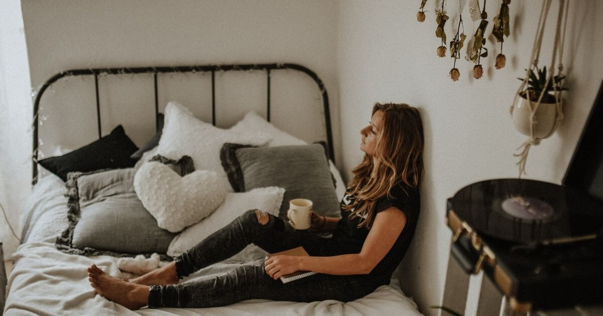 女性がベッドでコーヒーを飲んでいる画像