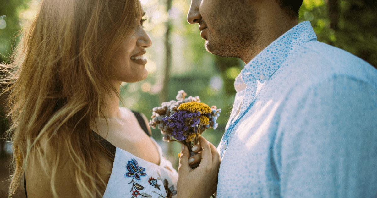 女性が花束を手に持ち男性と見つめ合っている画像