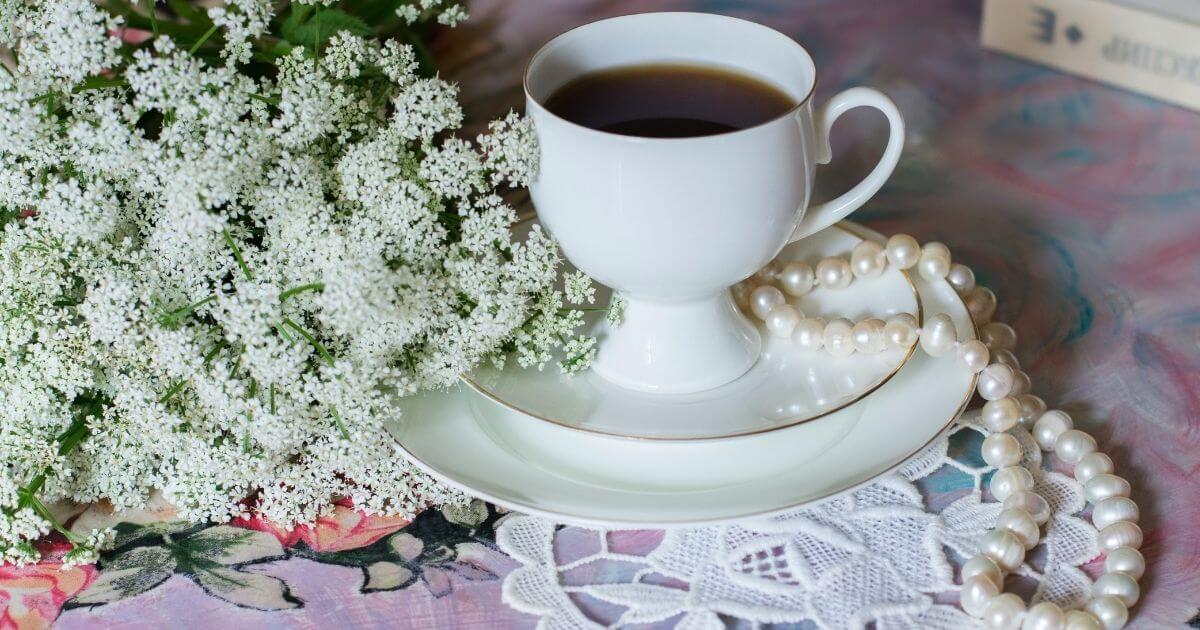 白いお花とコーヒーと真珠が置かれたテーブルの画像