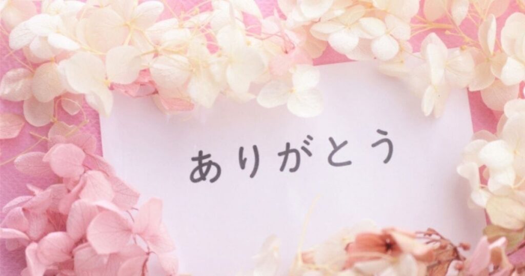 「ありがとう」と書かれたカードをピンクと白のアジサイのお花で囲んでいる画像