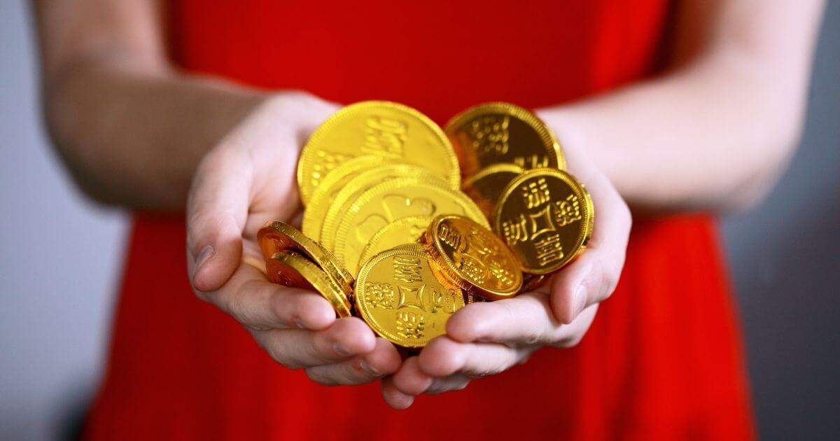 女性が金の紙に包まれたチョコレートを両手で持っている画像