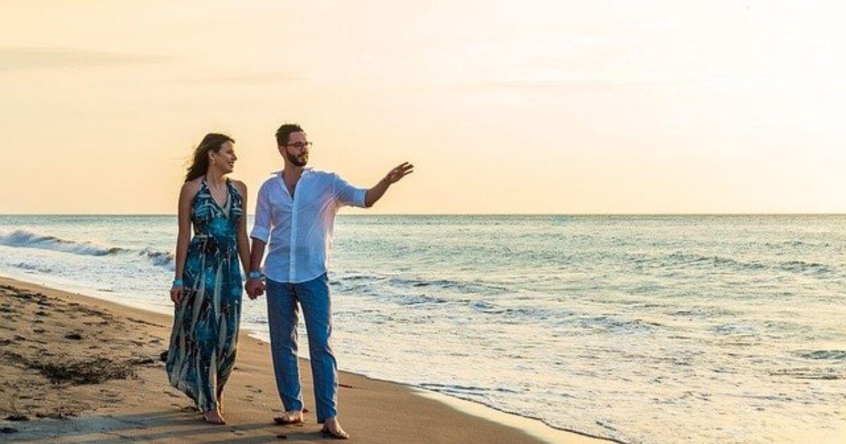 美しいビーチえ男女のカップルが手をつなぎ歩いている画像