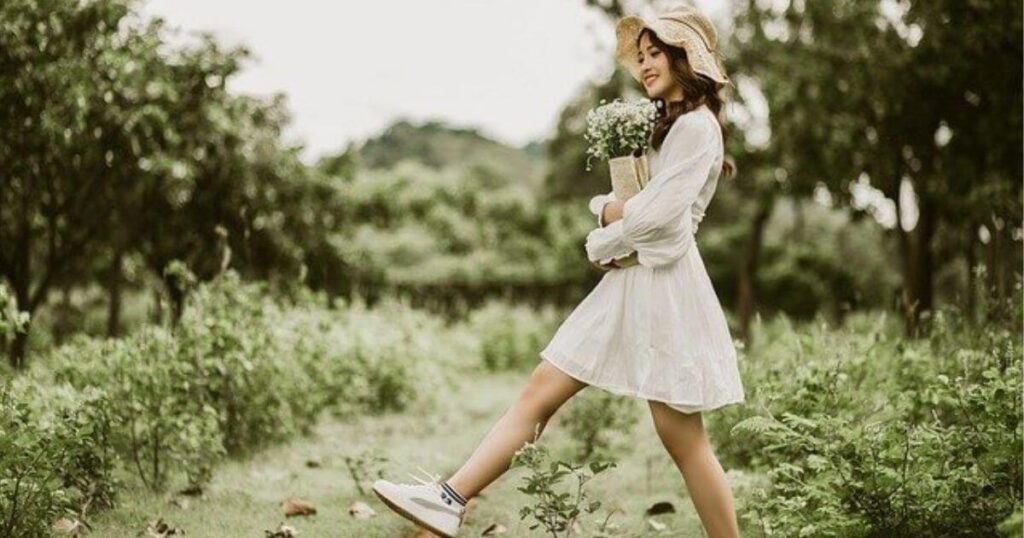 白いワンピースを着た女の子が花束を持って歩いている画像