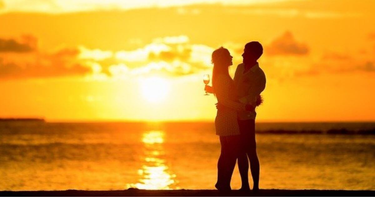 夕日が美しい背景に男女のカップルが見つめ合って立っている画像