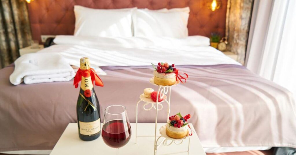 ホテルのベッドとワインとケーキの画像